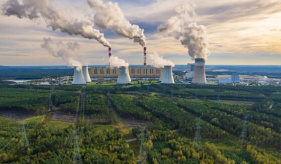 A coal-powered plant in Bełchatów, Poland pumps plumes of smoke into the air above the facility.