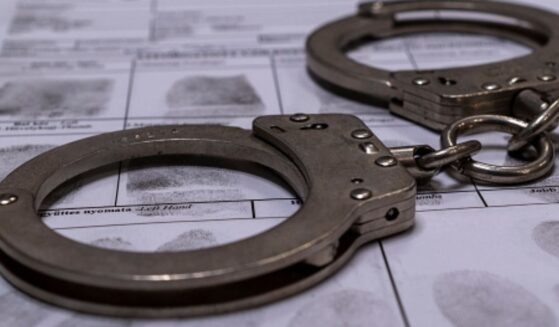 A pair of handcuffs sit on top of a fingerprinting chart in a dimly lit room.