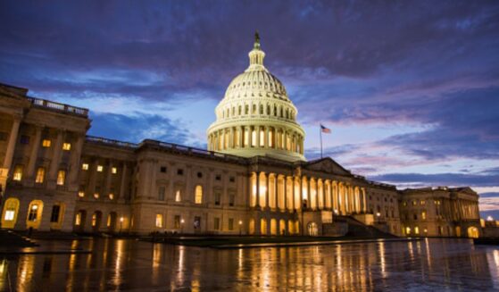 The Capitol Building stands on a dark night illuminated by interior lights.