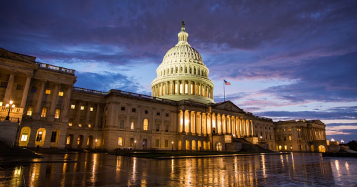 The Capitol Building stands on a dark night illuminated by interior lights.
