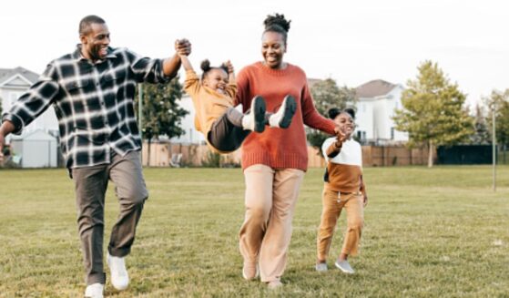 Parents play on a playing field with their young children.