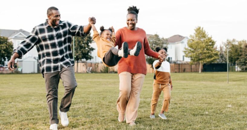 Parents play on a playing field with their young children.
