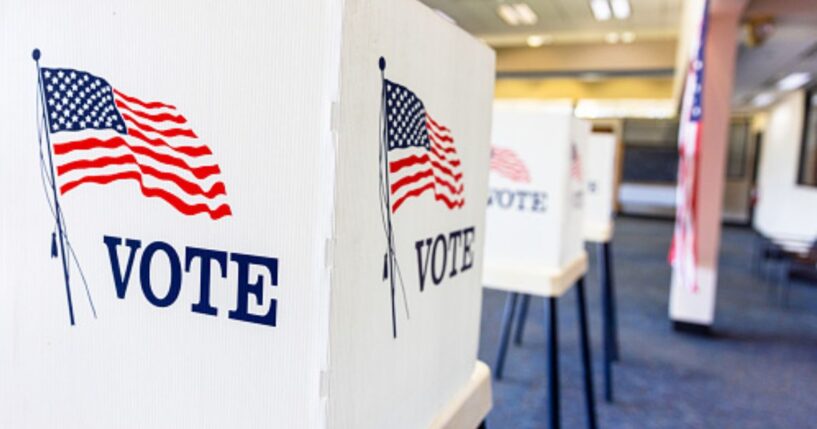 Rows of empty voting booths fill a bright civic center.