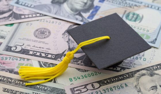 A graduation cap sits on a pile of money.