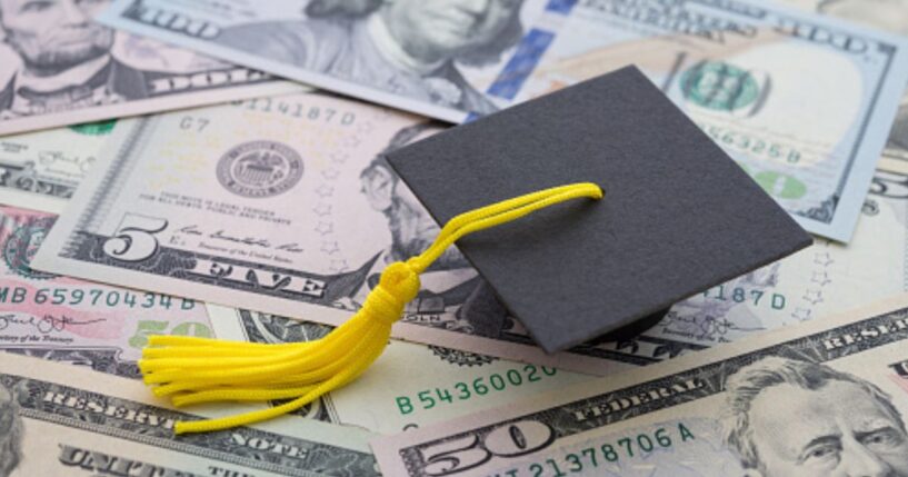 A graduation cap sits on a pile of money.