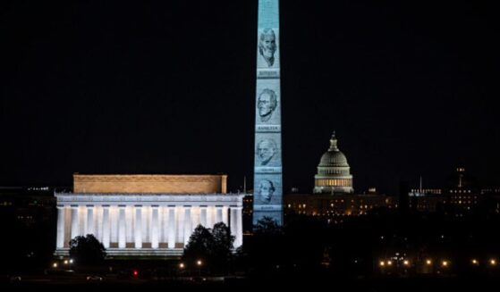 The Washington Monument stands illuminated with Founding Fathers’ faces on January 3, 2026.