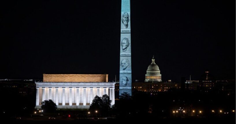 The Washington Monument stands illuminated with Founding Fathers’ faces on January 3, 2026.