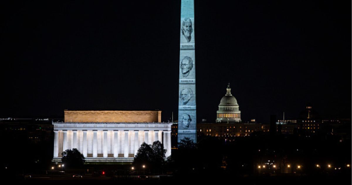 The Washington Monument stands illuminated with Founding Fathers’ faces on January 3, 2026.