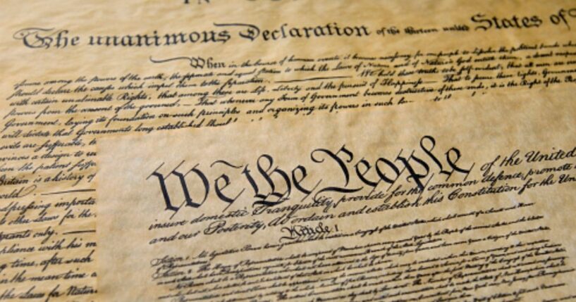 Pages of the Constitution are visible under warm lighting.
