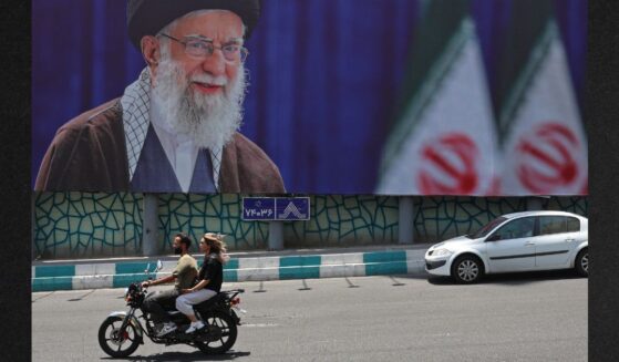 Motorists ride past a giant billboard bearing a picture of Iran's late supreme leader Ayatollah Ali Khamenei Thursday ahead of his funeral in Tehran.