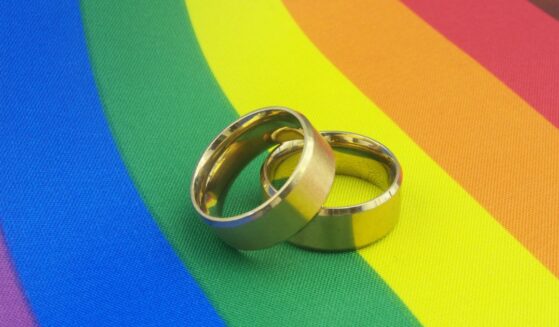 Gold wedding rings sit on top of an LGBT pride flag.
