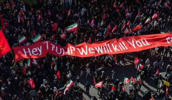 Mourners of the authoritarian Iranian Supreme Leader Ayatollah Ali Khamenei hold up a banner threatening the life of President Donald Trump on July 9, 2026 during a funeral procession for the leader in Mashhad, Iran.