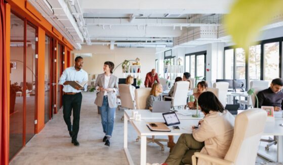 Employees work in and walk through a modern-looking workspace.