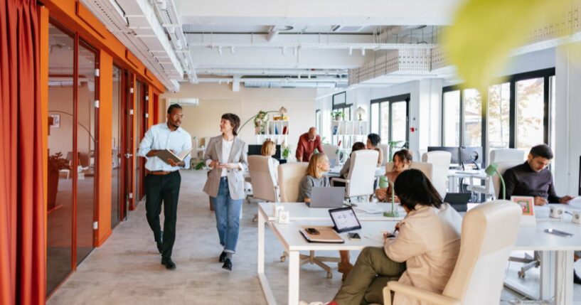 Employees work in and walk through a modern-looking workspace.