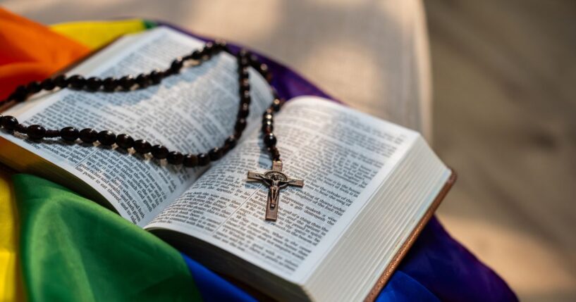 A Holy Bible sitting on top of a rainbow flag.