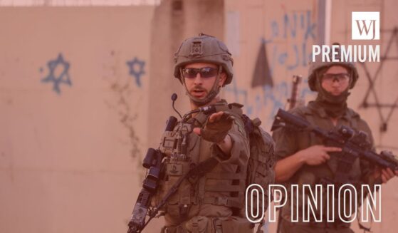 An armed Israeli soldier gestures while standing next to another soldier in the Old City of Hebron, the occupied West Bank, on June 27, 2026.