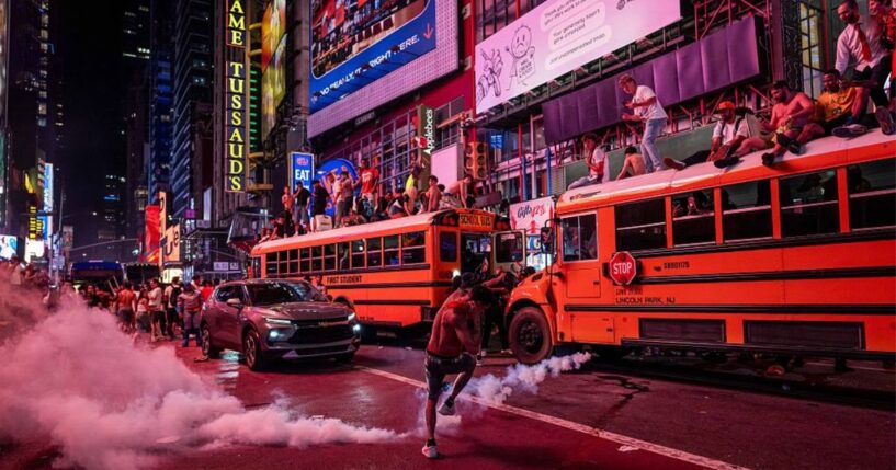 A person kicks a smoke canister as New York Knicks fans celebrate their win against San Antonio Spurs in Game 5 of the NBA Finals June 14 in Times Square in New York City. One exuberant fan reportedly set fire to a school bus.
