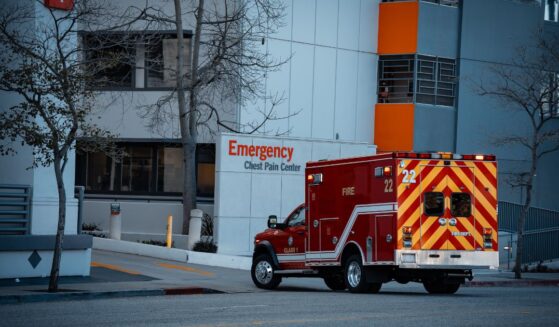 An emergency medical services vehicle is positioned near the entrance of a hospital's emergency department.