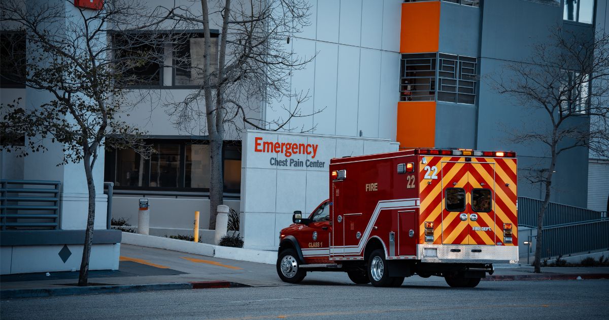 An emergency medical services vehicle is positioned near the entrance of a hospital's emergency department.