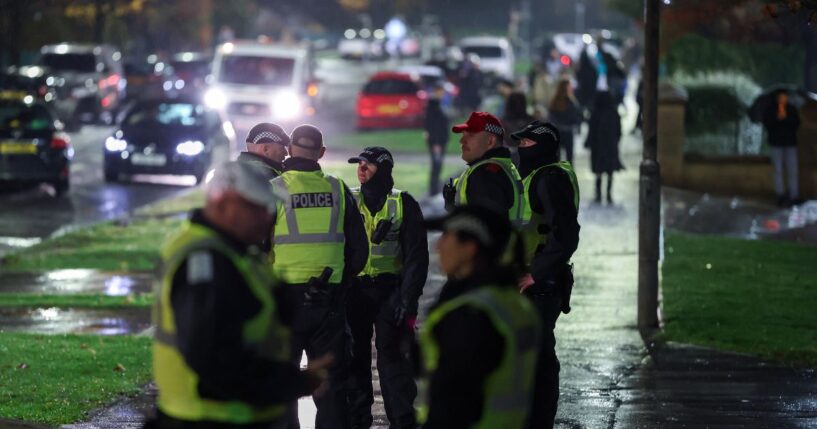 Police officers patrol the street as fireworks go off in the distance on Nov. 5, 2025, in Edinburgh, Scotland.