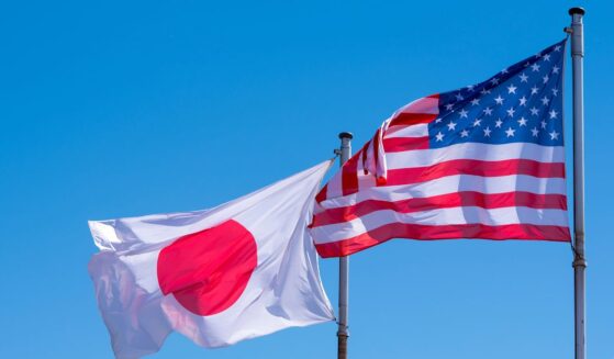 American and Japanese flags waving against a blue sky.