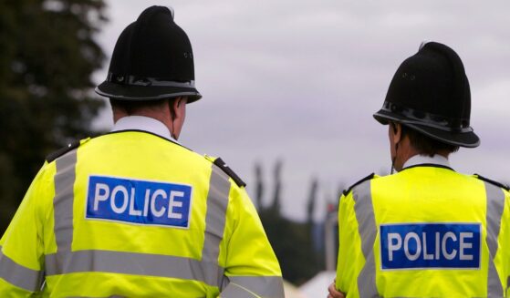 Two British police officers guard the entrance to the arena of a summer fair, on a typically gloomy British summer day.
