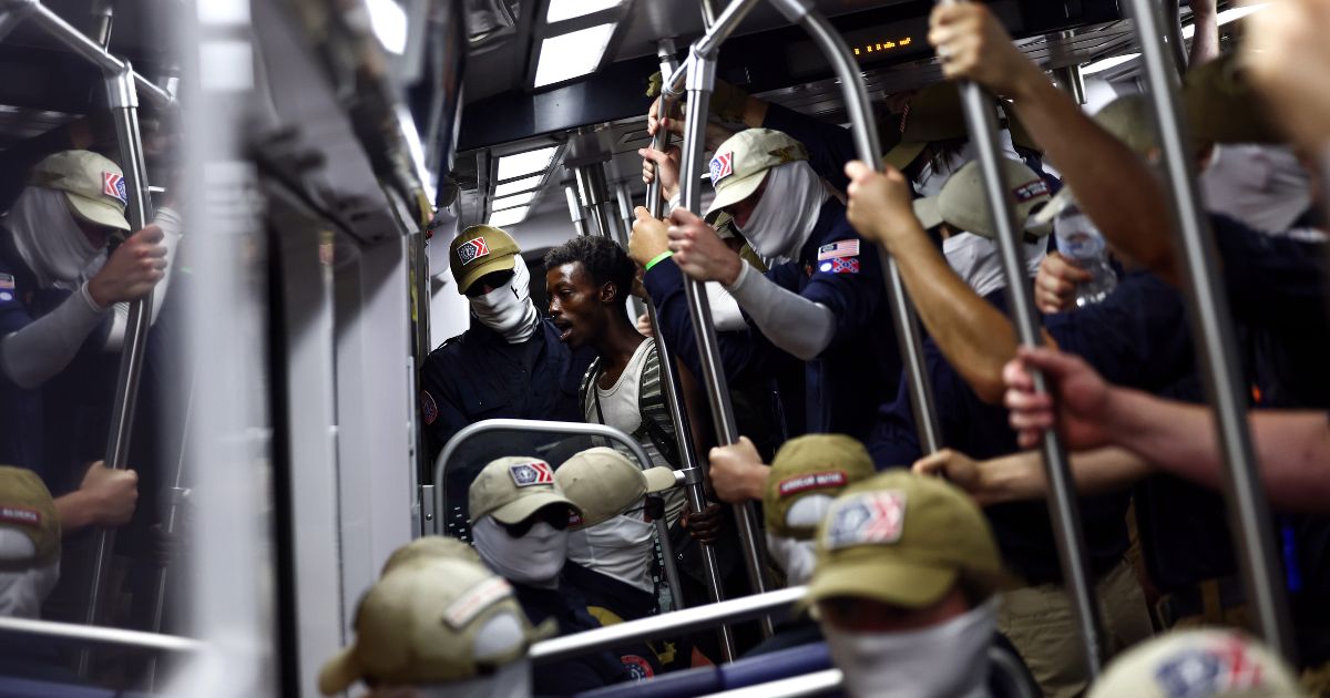 A passenger looks on as members of the white supremacist group Patriot Front ride the Washington Metro on July 4, 2026, in Washington, D.C.