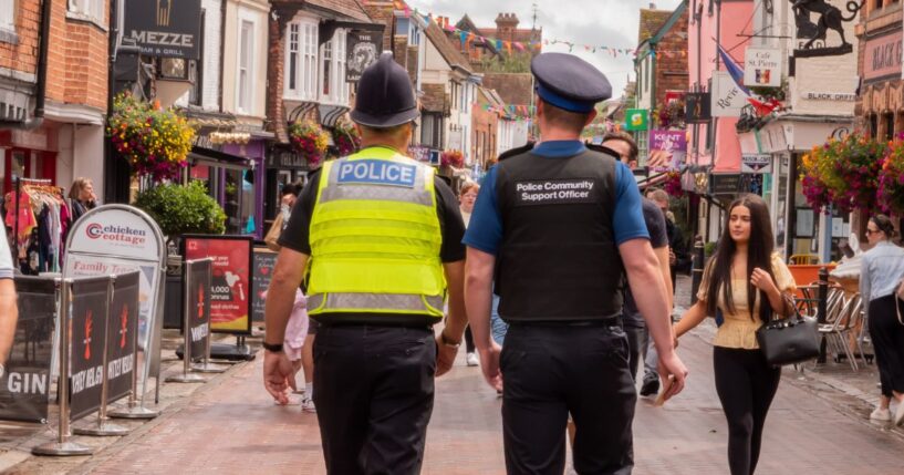 A policeman and a police community support officer walking down a busy street in Canterbury, Kent, United Kingdom, on Aug. 7, 2021.