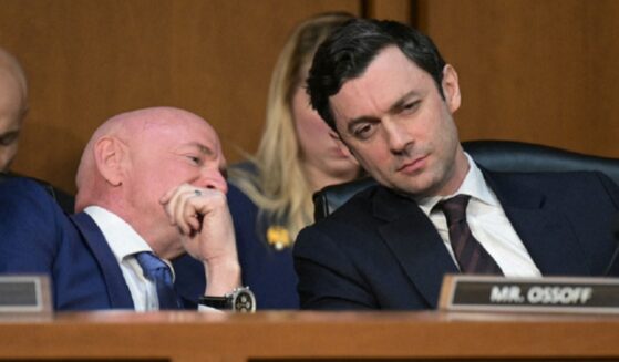 Democratic U.S. Sen. Jon Ossoff of Georgia, right, listens as Sen. Mark Kelly of Arizona whispers to him during a Senate March hearing.