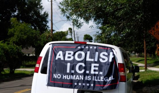 A banner reading "Abolish ICE, No Human is Illegal" is displayed on a van in Houston, Texas.