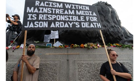 Two protesters hold a large placard blaiming the media for the death of Jason Arday Monday during a vigil in London's Trafalgar Square.