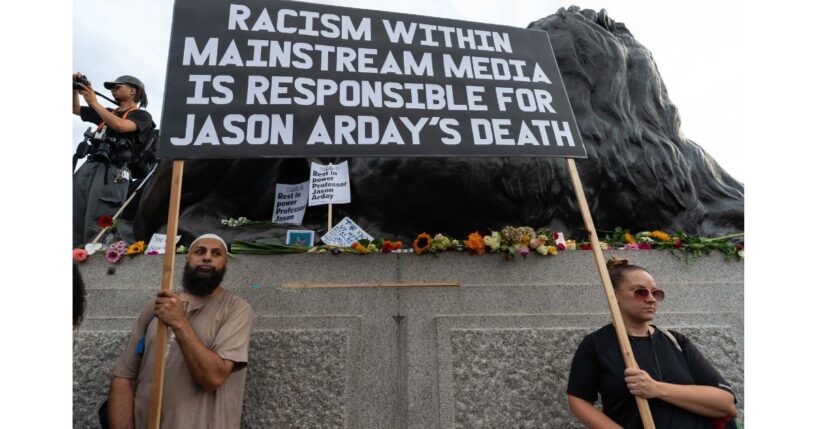 Two protesters hold a large placard blaiming the media for the death of Jason Arday Monday during a vigil in London's Trafalgar Square.
