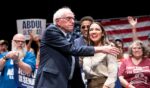 Sen. Bernie Sanders greets Rep. Alexandria Ocasio-Cortez at The People v. The Powerful rally at the Detroit Opera House on July 18, 2026, in Detroit, Michigan.