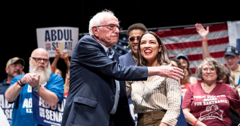 Sen. Bernie Sanders greets Rep. Alexandria Ocasio-Cortez at The People v. The Powerful rally at the Detroit Opera House on July 18, 2026, in Detroit, Michigan.