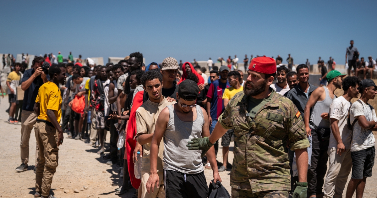 Migrants wait to receive water on the beach next to the CETI on Aug. 2, 2026, in Ceuta, Spain.