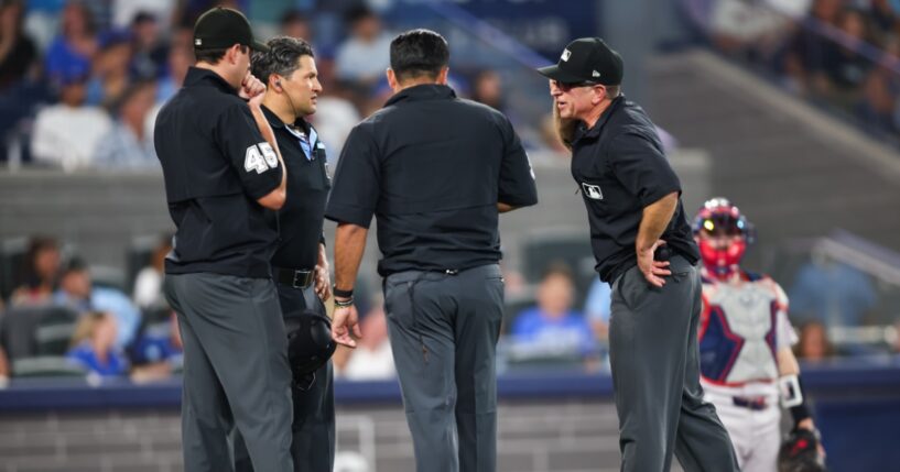 Umpires gather to review a play during the seventh inning of the MLB game between the Toronto Blue Jays and the Boston Red Sox at Rogers Centre on Aug. 10, 2026, in Toronto, Ontario, Canada.