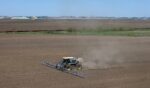 In an aerial view, a farmer applies a pre-emergent herbicide to a recently-planted corn field on May 7, 2026, near Mason City, Iowa.