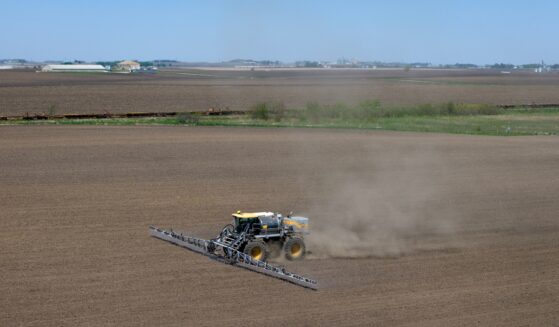 In an aerial view, a farmer applies a pre-emergent herbicide to a recently-planted corn field on May 7, 2026, near Mason City, Iowa.
