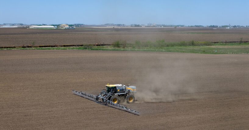 In an aerial view, a farmer applies a pre-emergent herbicide to a recently-planted corn field on May 7, 2026, near Mason City, Iowa.