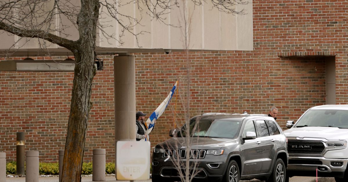 A person carries a flag of Israel from Temple Israel synagogue in West Bloomfield, Michigan, on March 13, 2026, after a person drove a vehicle into the synagogue a day earlier.