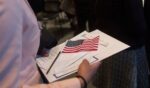 A woman brings paperwork covered by an American flag to immigration officials following a Naturalization Oath Ceremony at the John F. Kennedy Presidential Library and Museum on Feb. 8, 2017, in Boston, Massachusetts.