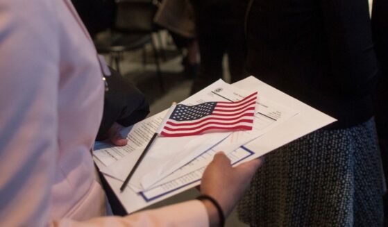A woman brings paperwork covered by an American flag to immigration officials following a Naturalization Oath Ceremony at the John F. Kennedy Presidential Library and Museum on Feb. 8, 2017, in Boston, Massachusetts.