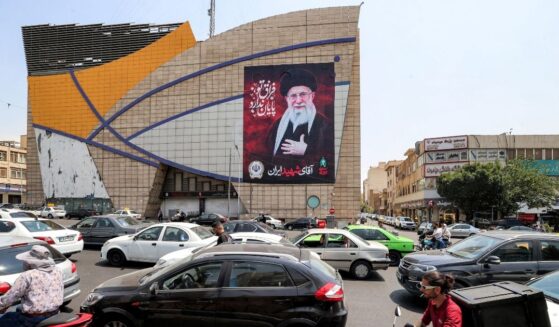 Motorists drive vehicles past a billboard depicting Iran's late supreme leader Ali Khamenei along a street in central Tehran on Aug. 8, 2026.