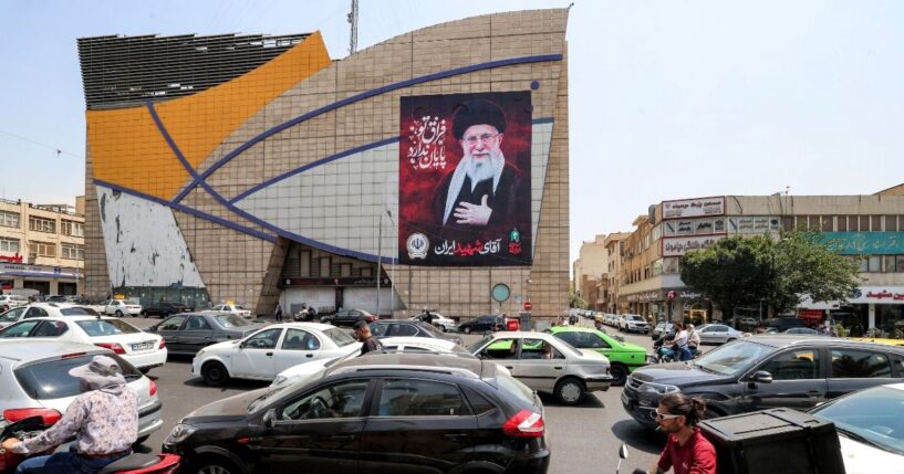 Motorists drive vehicles past a billboard depicting Iran's late supreme leader Ali Khamenei along a street in central Tehran on Aug. 8, 2026.