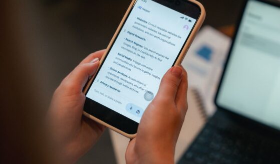 A woman looks at a phone screen with an AI user interface displayed on it.