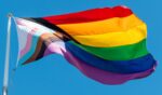 An LGBTQ flag flies in the sky.