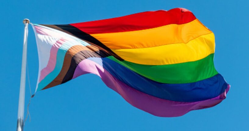 An LGBTQ flag flies in the sky.