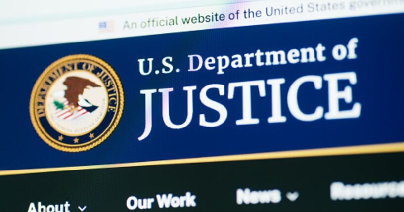 The Department of Justice website is pictured on a bright screen.