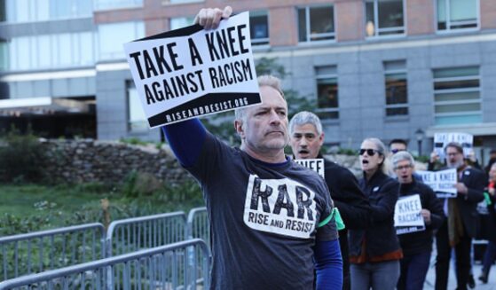 A man protesting racism with RAR stands holding a sign above his head leading a group of protesters outside the an NFL League Meeting on October 17, 2017 in New York City, NY.