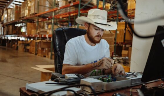 A man wearing a cowboy hat sits at a table and works.